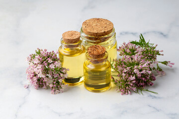 Essential oil in bottle with blooming valerian plant
