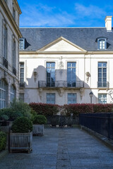 Paris, the square Saint-Gilles, public garden in the 3e arrondissement, with typical buildings in background 
