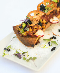 Elegante aperitivo de médula ósea con guarnición gourmet en plato blanco