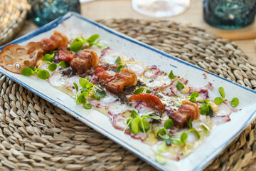 Octopus Carpaccio with Tomato Garnish and Microgreens on a White Plate
