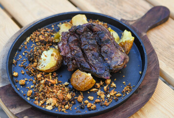 Delicioso bistec y patatas asadas en una sartén de hierro fundido