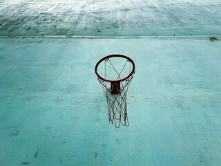 A weathered basketball hoop stands out against a textured blue wall, capturing the essence of urban courts and still moments in sports culture.