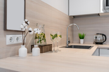 built-in kitchen with white cabinets. wooden table top. microwave oven, electric kettle, steel sink...