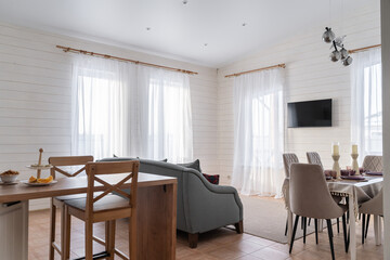 design of kitchen combined with a living room in a country house. Large sofa with decorative...