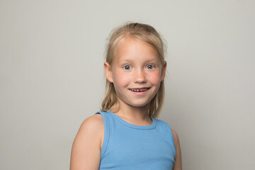 Laughing young child girl standing against white wall background
