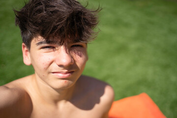 Selfie of a teenager boy relaxing outdoors on summer day: portrait of happy adolescent boy enjoying sunlight with copy space
