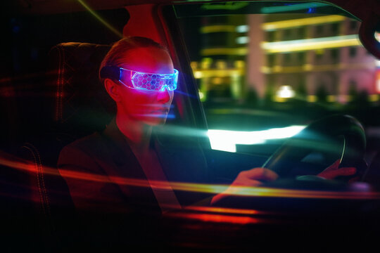 Woman in Futuristic High-tech VR Eyewear driving car in night ci