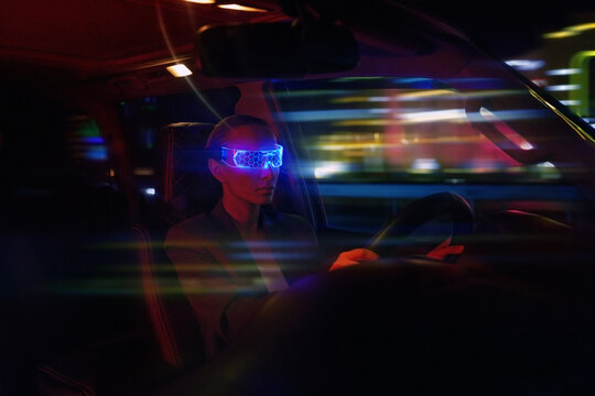 Woman in Futuristic High-tech VR Eyewear driving car in night ci