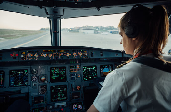 Female pilot in commercial airplane cockpit preparing for takeoff