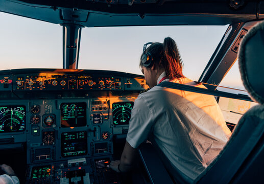 Female pilot in airplane cockpit during golden hour flight