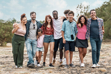Diverse group of friends walking together outdoors in nature - multicultural different people...