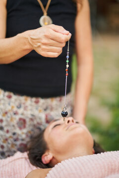 Therapist using pendulum during crystal healing therapy session