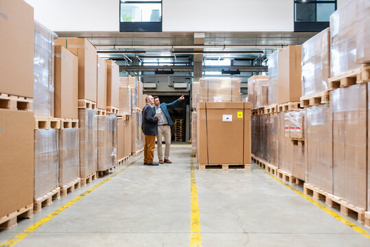Two employees having a meeting in a warehouse surrounded by cardboard boxes