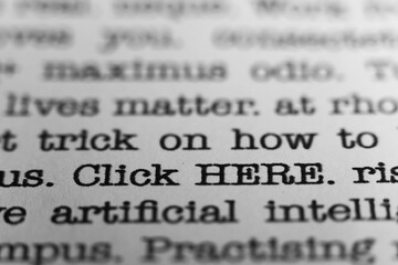 Click HERE. Text printed on a page. A piece of paper with a phrase written in retro typewriter font