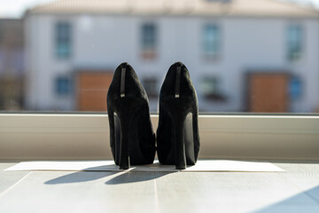Black ladies pumps on the floor in front of a window