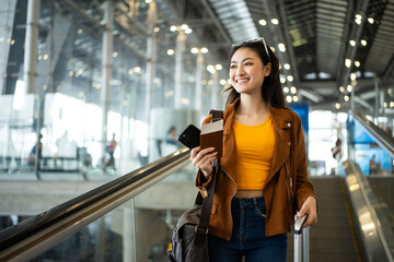 happy young asian woman traveler holding boarding pass ticket, passport and smartphone at the...