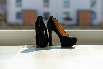 Black ladies pumps on the floor in front of a window