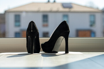 Black ladies pumps on the floor in front of a window