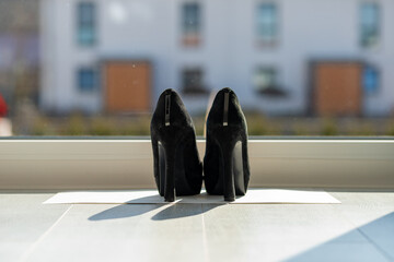 Black ladies pumps on the floor in front of a window