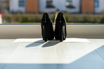 Black ladies pumps on the floor in front of a window