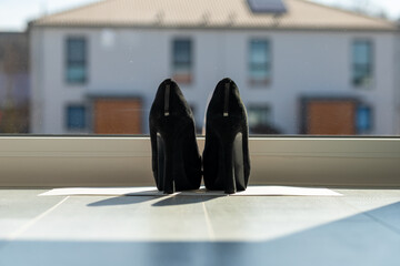 Black ladies pumps on the floor in front of a window
