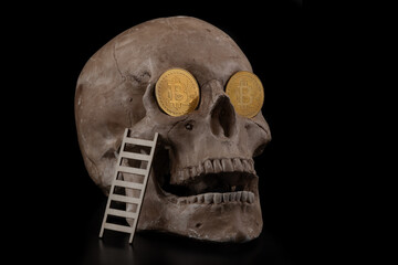 Coins with the symbol of the cryptocurrency Bitcoin in the shapes of a human skull on a black...