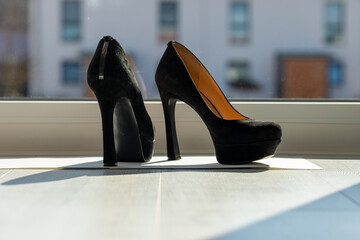Black ladies pumps on the floor in front of a window