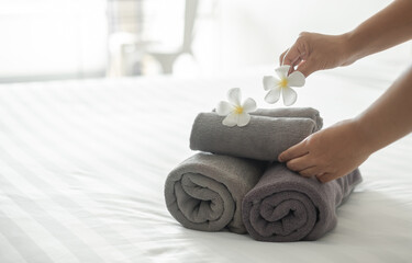 A hotel maid stacked towels on the bed and placed flowers on the towels in a hotel room
