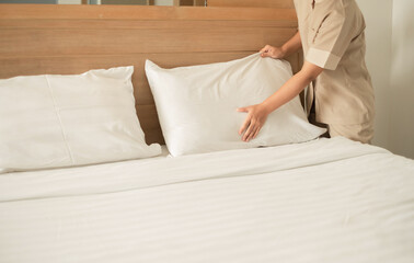 The hotel maid cleans and makes the bed in the hotel room