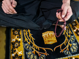 close up of a man's hands praying while counting prayer beads after performing the prayer
