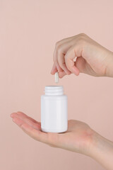 Mock-up of a tube for medicines or vitamins with the lid open. In a woman's hand. Product packaging mockup. Empty tube with space for logo and text.