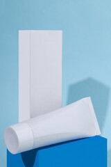 Mockup of a tube with cream on the table.  Layout of product packaging. Empty white tube with cream. Place for logo and text. Red background