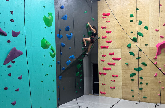 Teenage girl at indoor climbing wall. Kid having fun at bouldering wall. Child learning at climbing class. Sports healthy lifestyle. Youth at climbing summer camp
