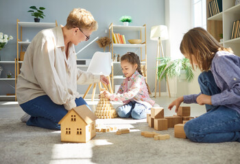 Happy family together, grandchildren and grandmother friendly playing toys at home, sit laughing on...