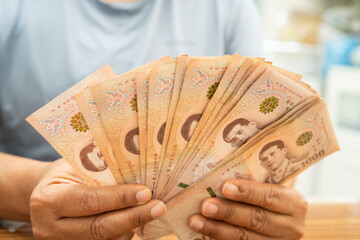 Asian woman counting Thai baht banknote money, investment economy, accounting business and banking.