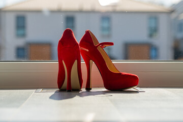 Red ladies pumps on the floor in front of a window