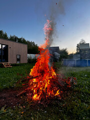 Large fire in the backyard of a country house in the evening in the summer. Vertical orientation.