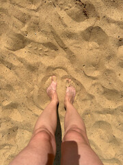 Two feet on the yellow sand. Vertical orientation.