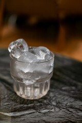 a glass filled with ice, possibly for a cocktail or shochu. The glass is on a dark marble surface.