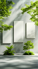 Fototapeta premium Three blank canvases hang on a light grey wall, flanked by lush green foliage and dappled sunlight. A minimalist, serene scene ideal for showcasing artwork or product displays