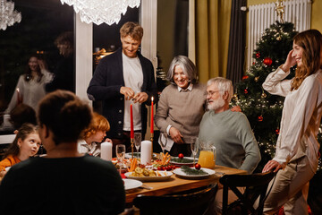 The happy White family gathered around the table for Christmas dinner, enjoying the food and spending quality time together. A concept of family, bonding, and human relationships.