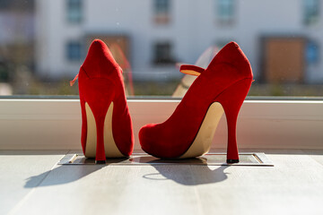 Red ladies pumps on the floor in front of a window
