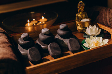 Flat lay of Thai spa essentials including stones, oils, lotus flowers, and towels arranged for a massage setting.