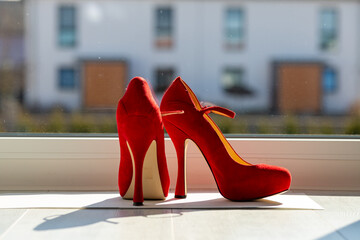 Red ladies pumps on the floor in front of a window