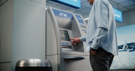 Cash Machine in Crowded Airport Terminal: Man Pressing Buttons on ATM Keypad, Entering PIN Code,...