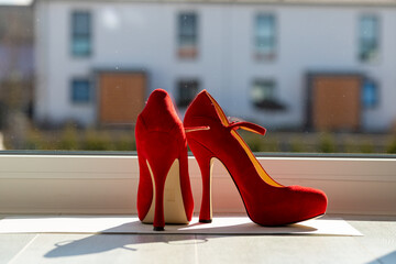 Red ladies pumps on the floor in front of a window