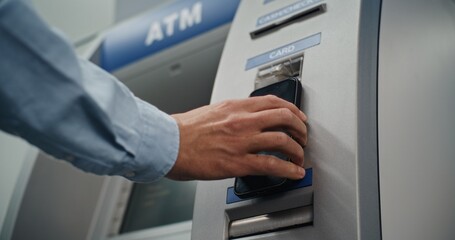 Modern Cash Machine: Unrecognizable Man Putting Smartphone to NFC Reader for Contactless Cash Withdrawal Transaction, Entering PIN Code on ATM Machine. Banking Services, Financial Operations. Close Up