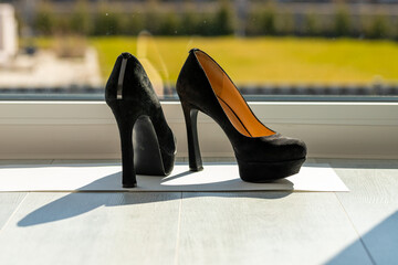 Black ladies pumps on the floor in front of a window