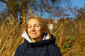 Joyful woman savoring a moment of peace in nature during a sunny autumn day surrounded by golden grass and trees