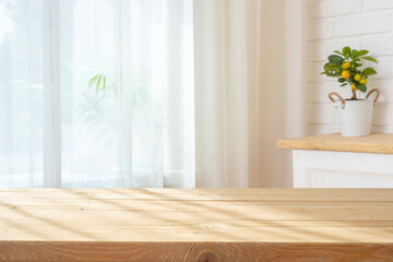 Wooden planks table with sunlight shadows for product display on curtained window interior background